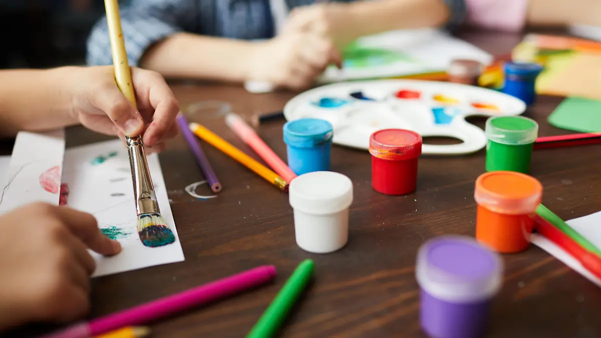 Nahaufnahme einer Malerei mit Kinderhänden und bunten Farben.