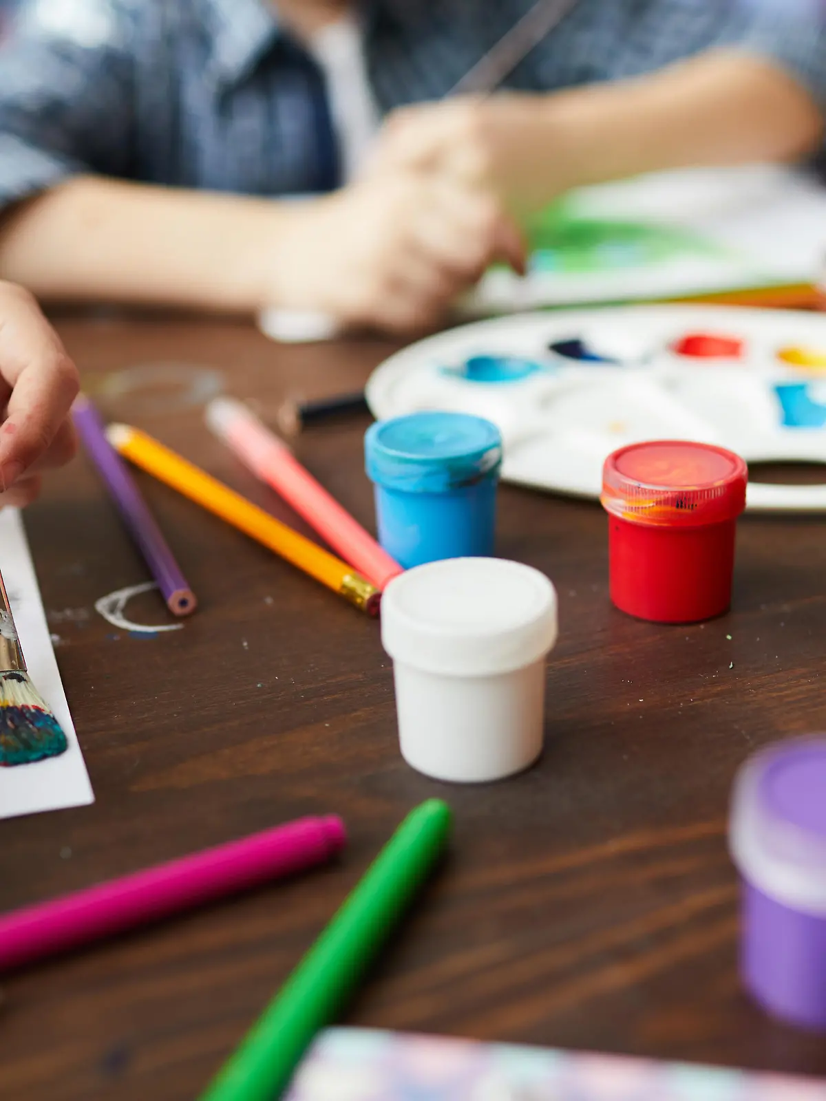 Nahaufnahme einer Malerei mit Kinderhänden und bunten Farben.