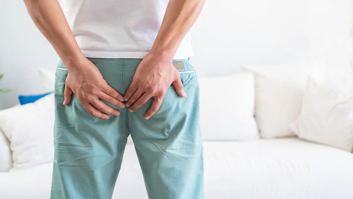 Man suffer from hemorrhoids. Man hand holding his bottom because hemorrhoids. Man with hemorrhoids and constipation. The pain caused by hemorrhoid