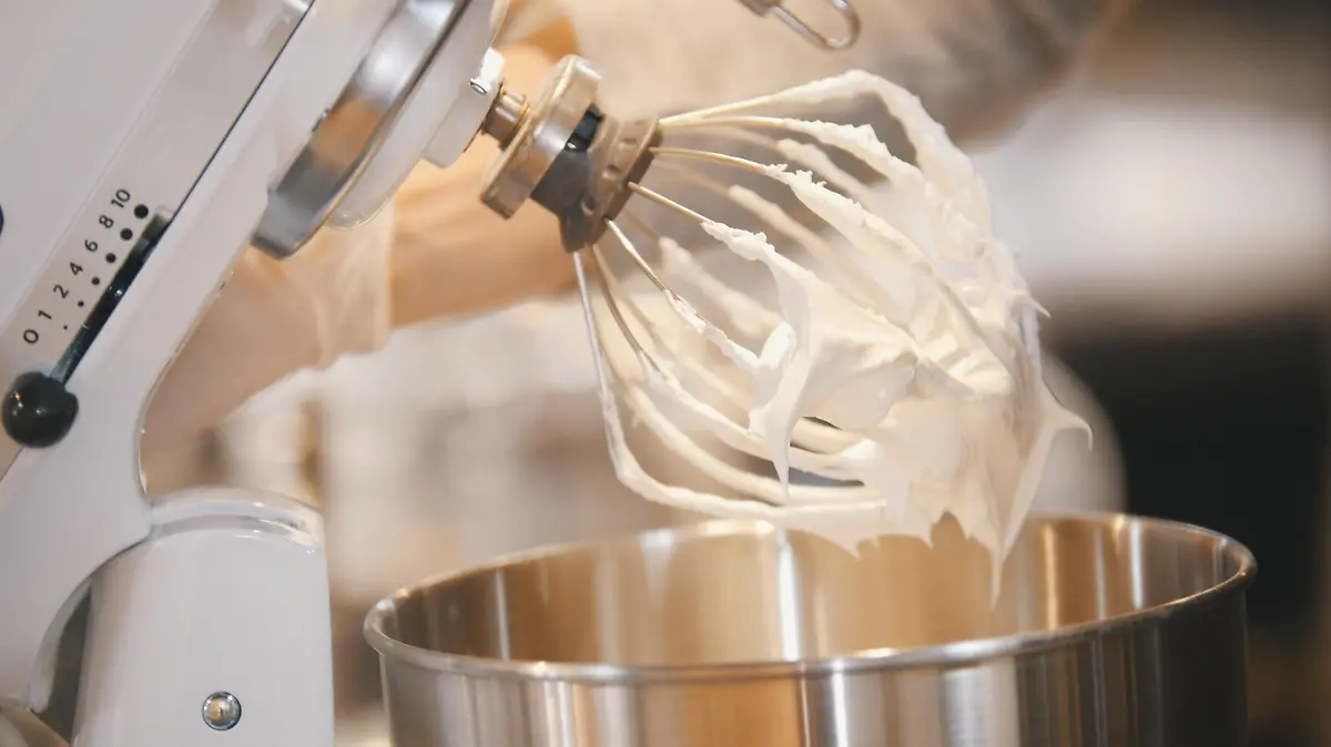 Process of cooking meringue whipped egg whites on mixer whisk , close up