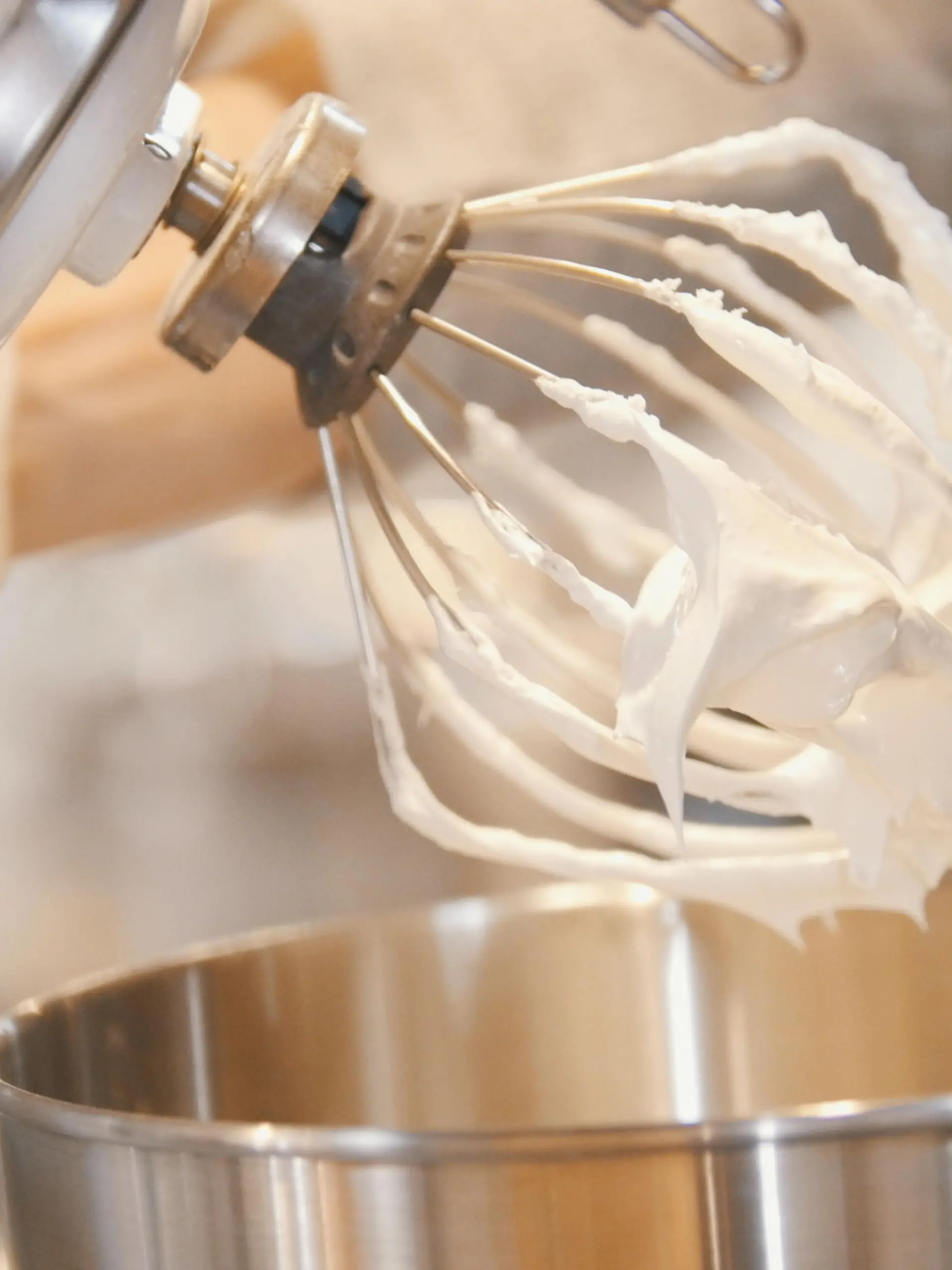 Process of cooking meringue whipped egg whites on mixer whisk , close up