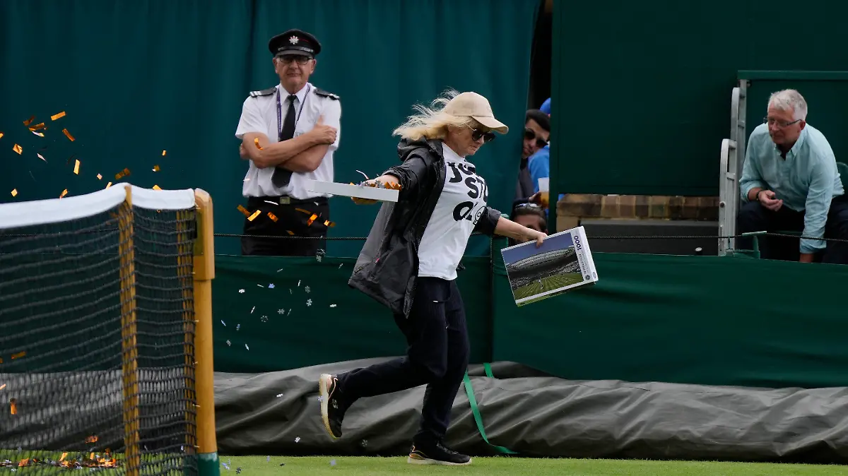 A Just Stop Oil protester runs onto Court 18 and releases confetti on day three of the Wimbledon tennis championships in London, Wednesday, July 5, 2023. (AP Photo/Alastair Grant)