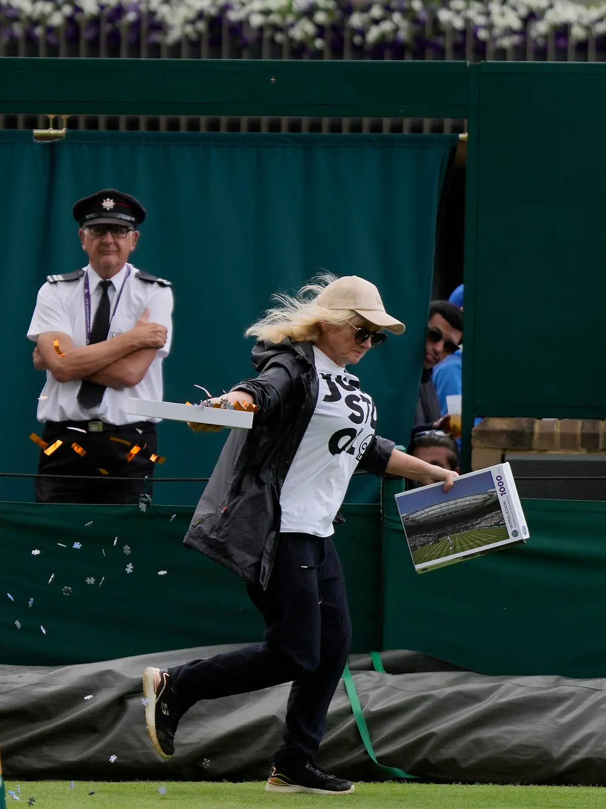A Just Stop Oil protester runs onto Court 18 and releases confetti on day three of the Wimbledon tennis championships in London, Wednesday, July 5, 2023. (AP Photo/Alastair Grant)