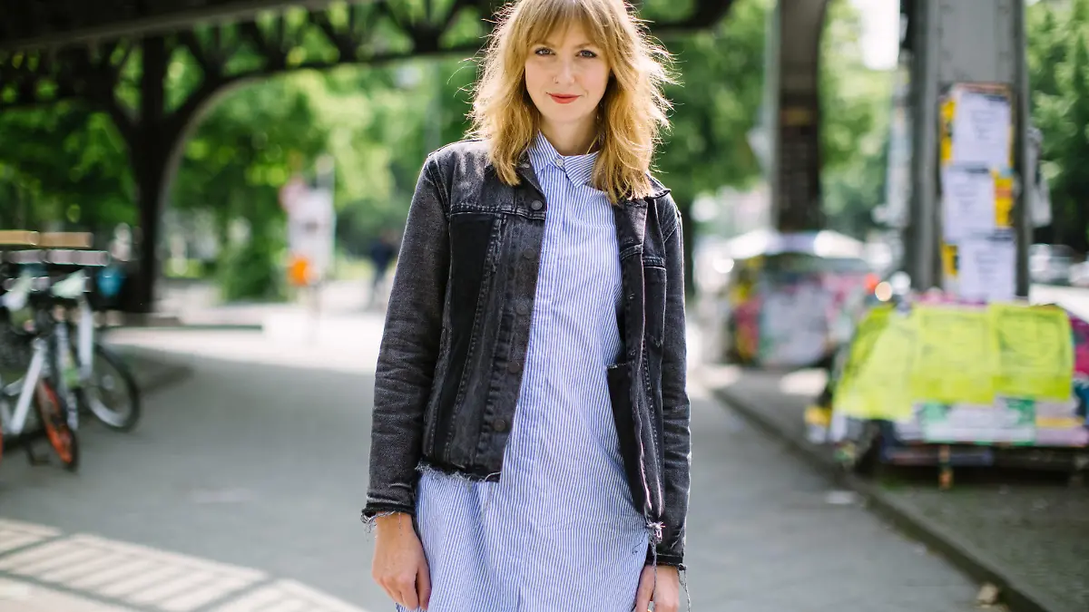 Portrait of beautiful young woman walking on the city street. Attractive female wearing a jacket looking at camera and smiling.