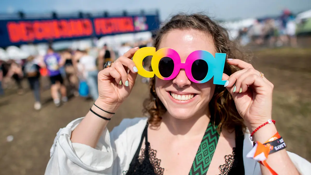 18.07.2024, Niedersachsen, Nordholz: Festivalbesucherin Lynn steht mit einer bunten Sonnenbrille auf dem Festivalgelände des Deichbrand Festivals. Das Open-Air-Festival mit rund 60.000 Besuchern findet vom 18. bis zum 21. Juli statt. Foto: Hauke-Christian Dittrich/dpa +++ dpa-Bildfunk +++