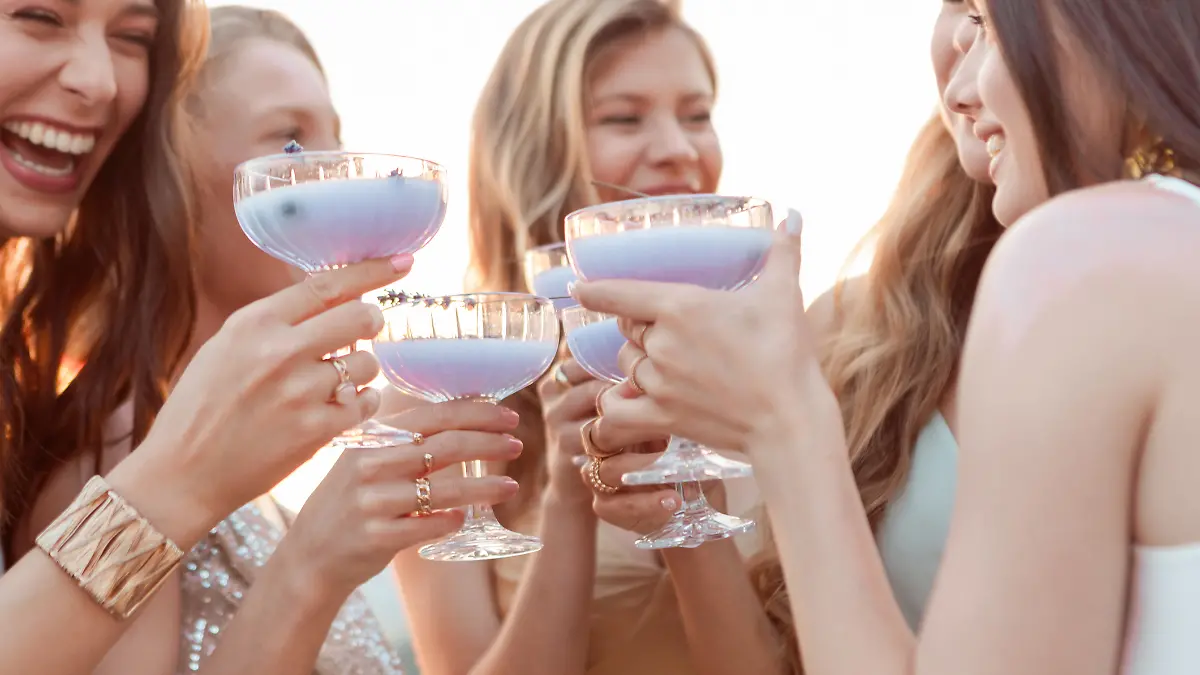 Eine Freundesgruppe, bestehend aus Frauen, stößt mit Lavendel Spritz an. 