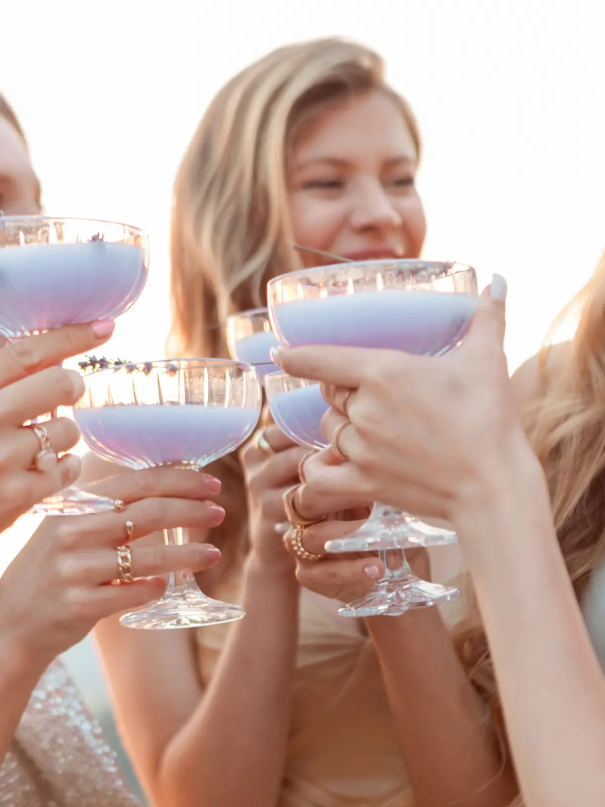 Eine Freundesgruppe, bestehend aus Frauen, stößt mit Lavendel Spritz an. 
