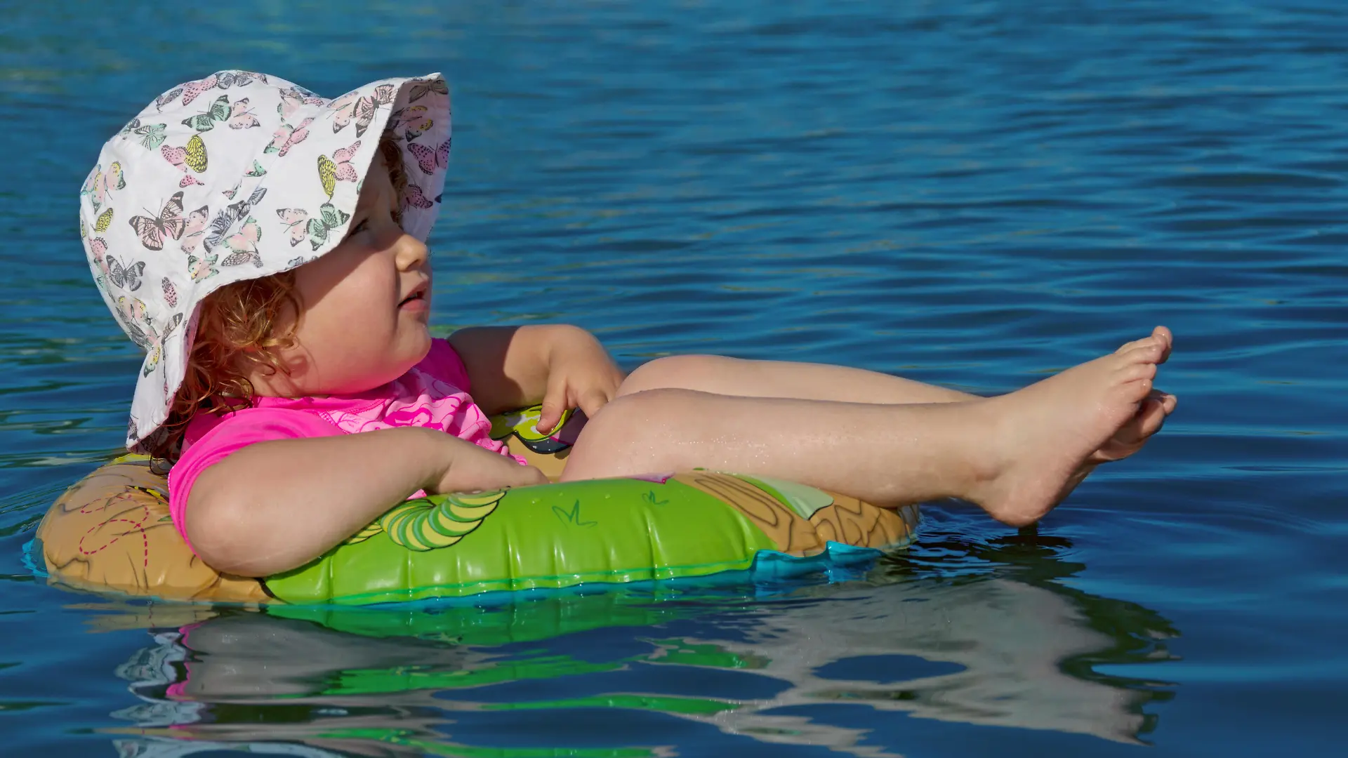 Ein Mädchen liegt in einem Schwimmring und treibt auf dem Wasser (Symbolbild)