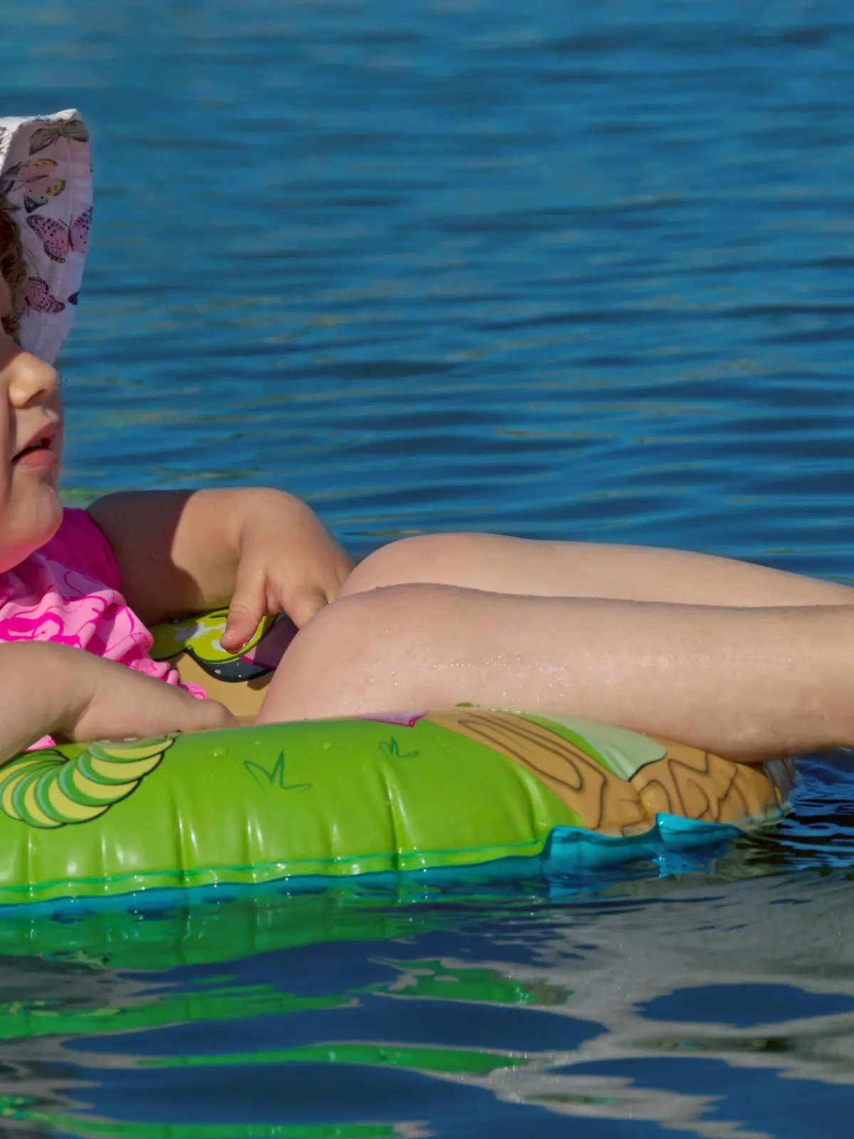 Ein Mädchen liegt in einem Schwimmring und treibt auf dem Wasser (Symbolbild)