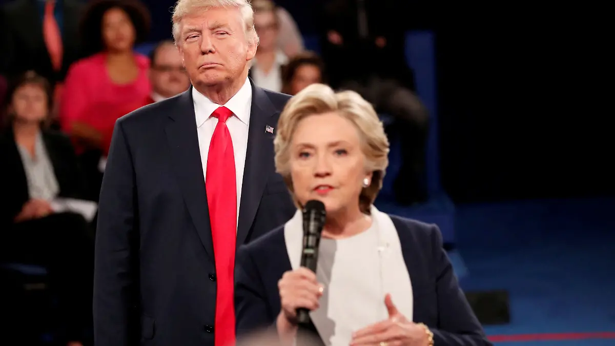 Hillary Clinton spricht während einer Debatte ins Mikrofon. Hinter ihr steht Donald Trump