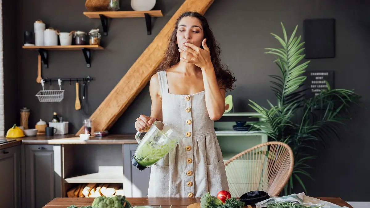 Frau mixt grünen Smoothie.