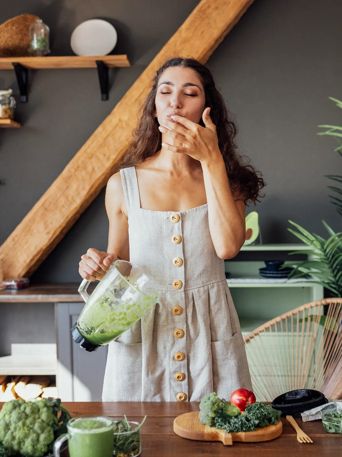 Frau mixt grünen Smoothie.