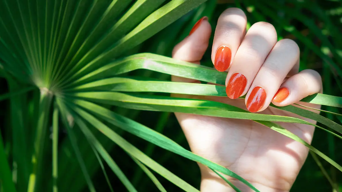 Frau trägt orangenen Nagellack.