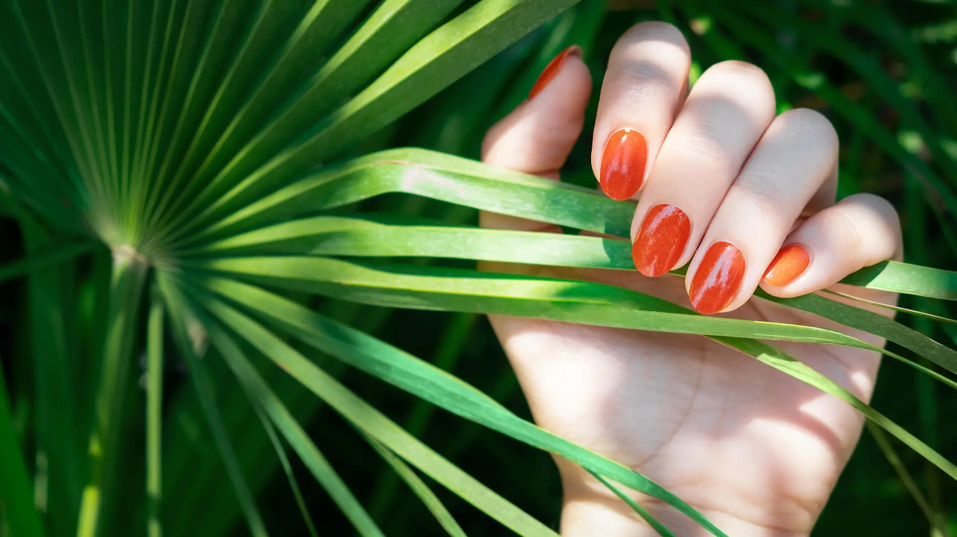 Frau trägt orangenen Nagellack.