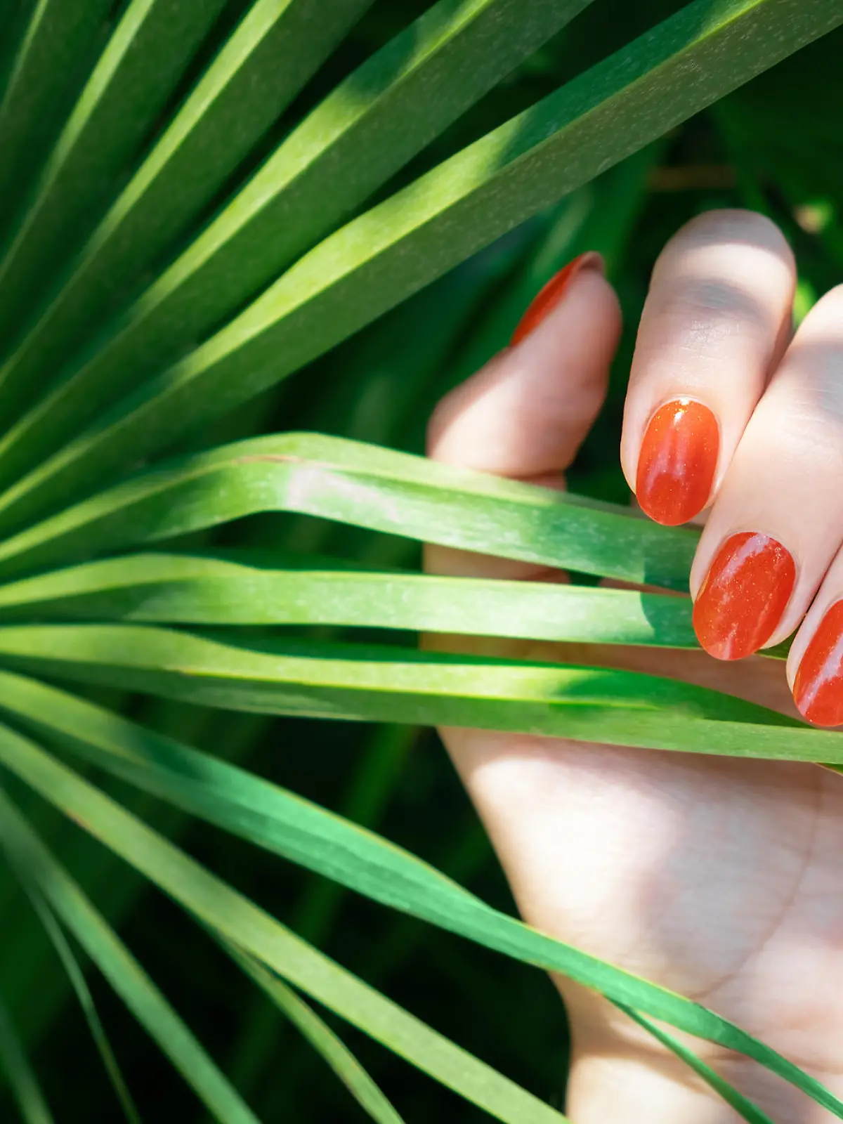 Frau trägt orangenen Nagellack.