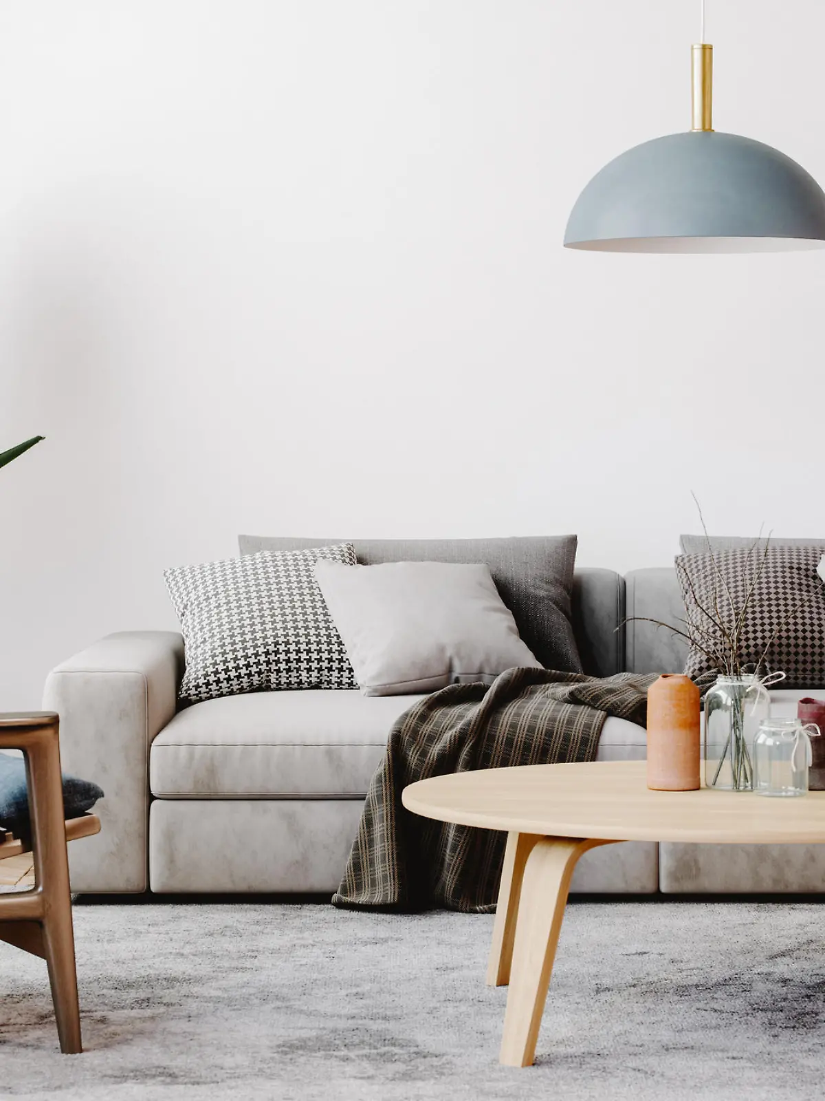 Modern living room setup with classic parquet floor. Furnished with light gray sofa, blue arm chair with wooden frame, modern blue ceiling lamp, wooden coffee table and gray carpet.