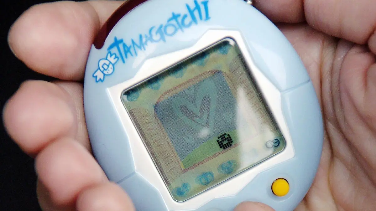 ARCHIV - 25.06.2004, Hamburg: Eine junge Frau spielt mit ihrem Tamagotchi. (Zu dpa: "Elektro-Hype: Tamagotchi übten Beziehung zwischen Mensch und Maschine") Foto: Maurizio Gambarini/dpa-Zentralbild/dpa +++ dpa-Bildfunk +++