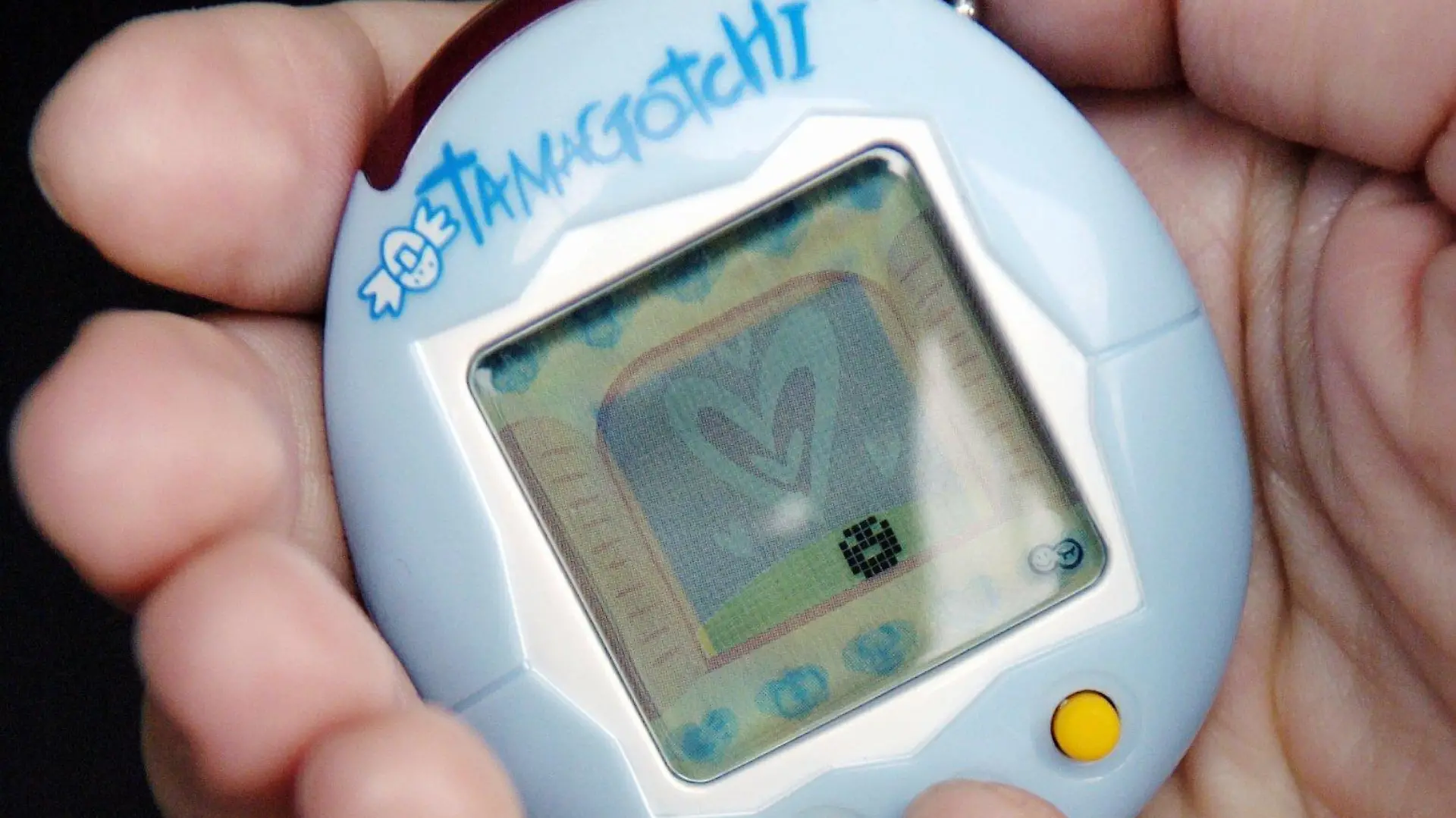 ARCHIV - 25.06.2004, Hamburg: Eine junge Frau spielt mit ihrem Tamagotchi. (Zu dpa: "Elektro-Hype: Tamagotchi übten Beziehung zwischen Mensch und Maschine") Foto: Maurizio Gambarini/dpa-Zentralbild/dpa +++ dpa-Bildfunk +++