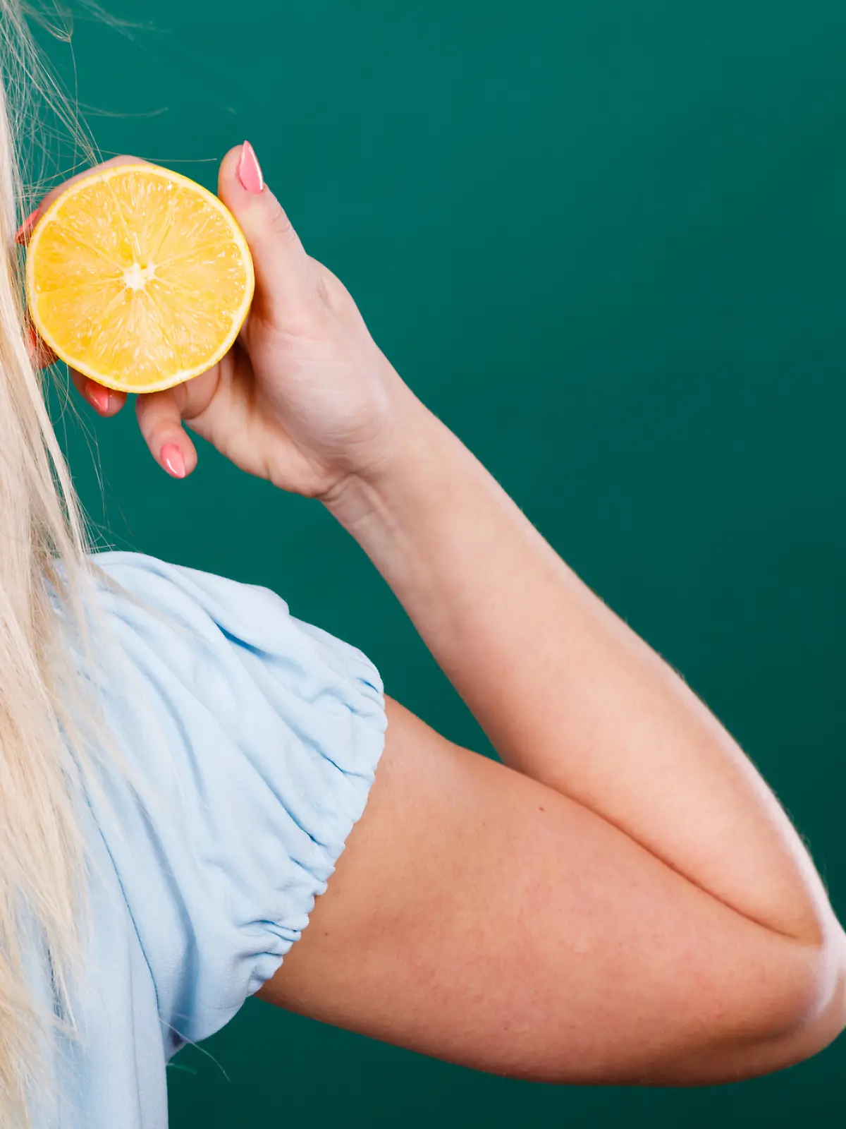 Eine blonde Frau hält eine Zitrone in der Hand.