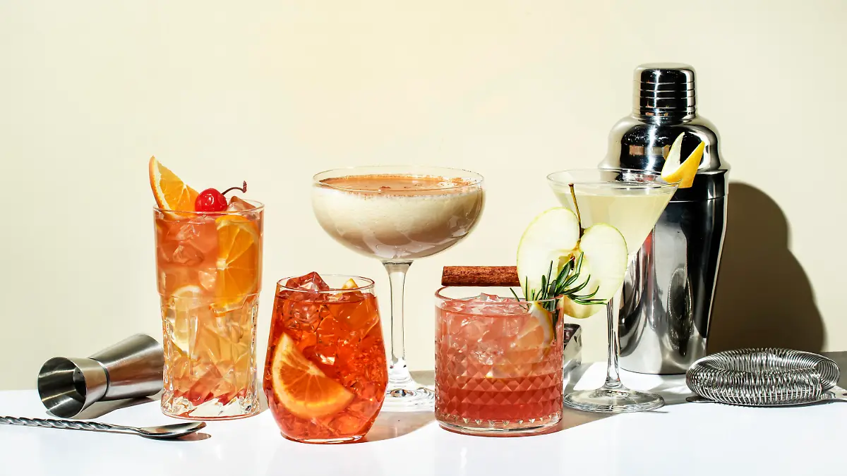 Cocktail party. Bright fruity and citrus alcoholic drinks with gin, vodka, vermouth and juice. Beige background, hard light, shadow pattern. Banner