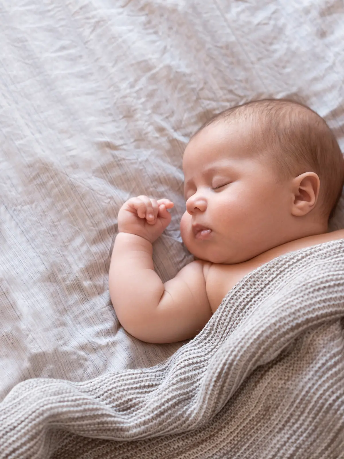 Ein Baby schläft friedlich in seinem Bettchen.