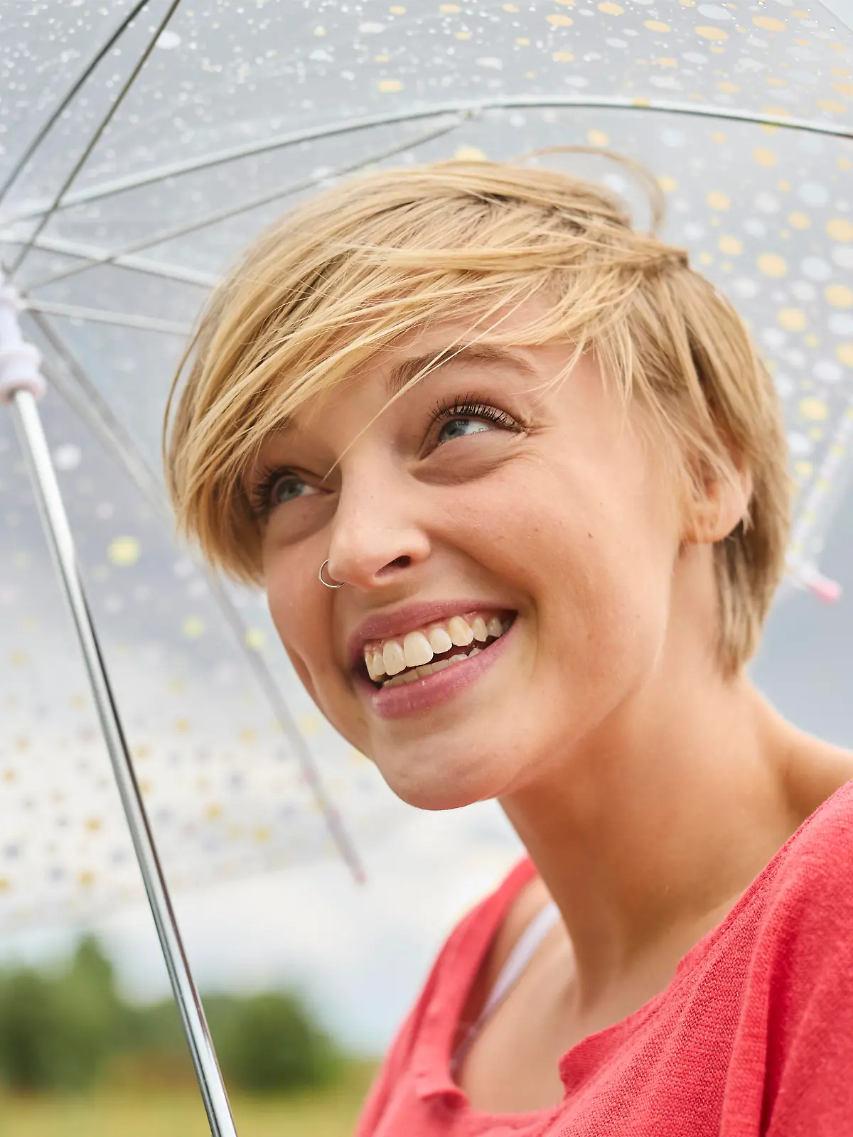 Happy young blond woman with umbrella on rainy day || Modellfreigabe vorhanden