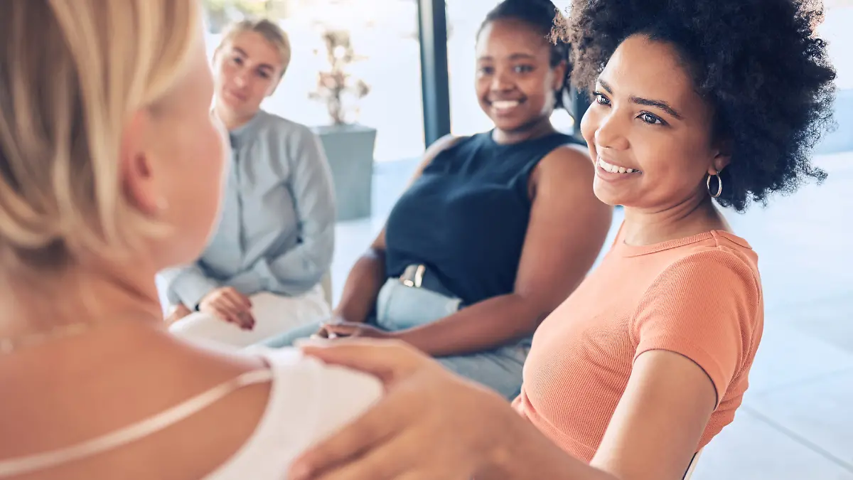 Eine Frau beschwichtigt und hilft einer anderen Frau in einem Arbeitskreis.