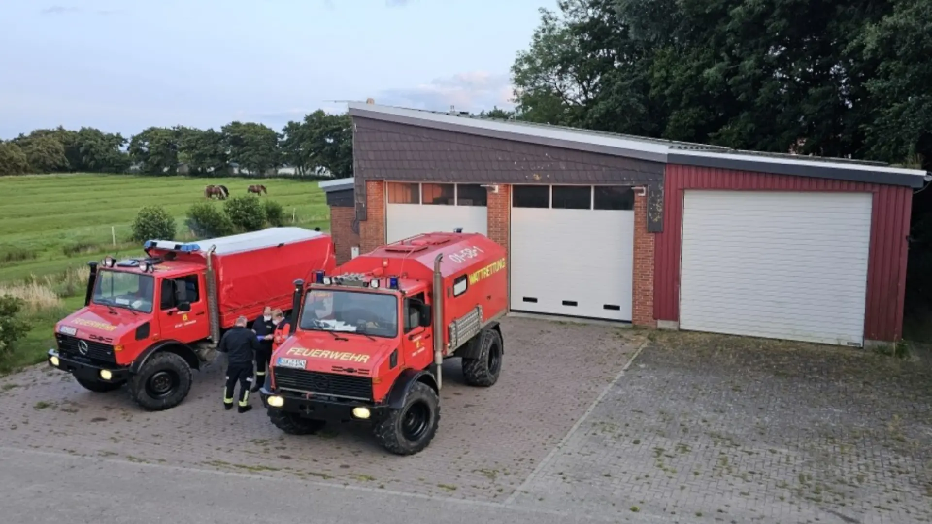 Zwei Feuerwehrautos vor ihren Garagen.