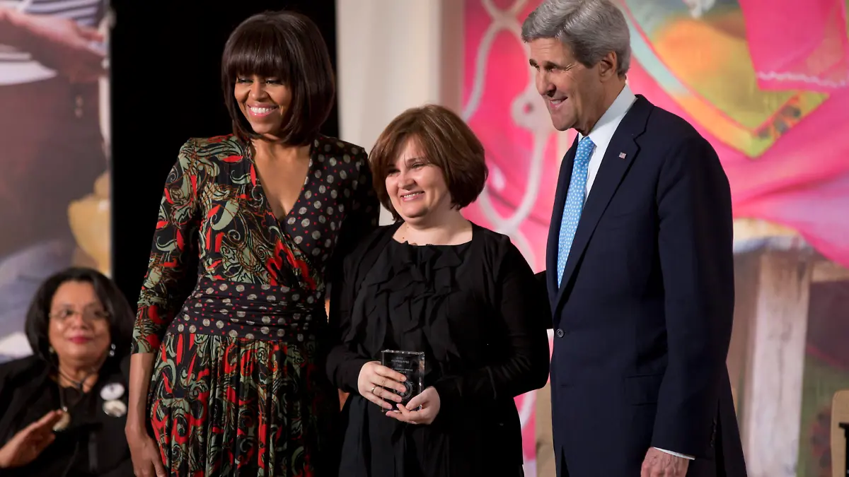 epa03615602 First Lady Michelle Obama (L) and Secretary of State John Kerry (R) award Elena Milashina of Russia (C) the International Women of Courage Award at the State Department in Washington DC, USA, 07 March 2013. EPA/JIM LO SCALZO ++