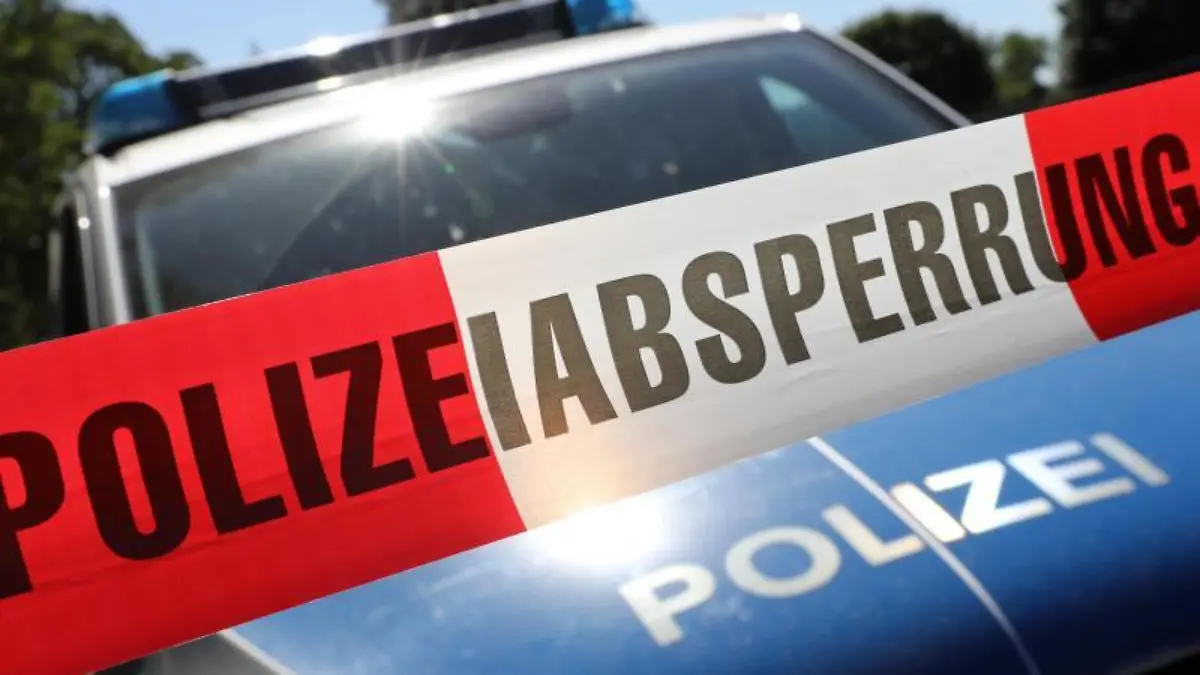 Eine Polizeiabsperrung hängt vor einem Polizeiauto