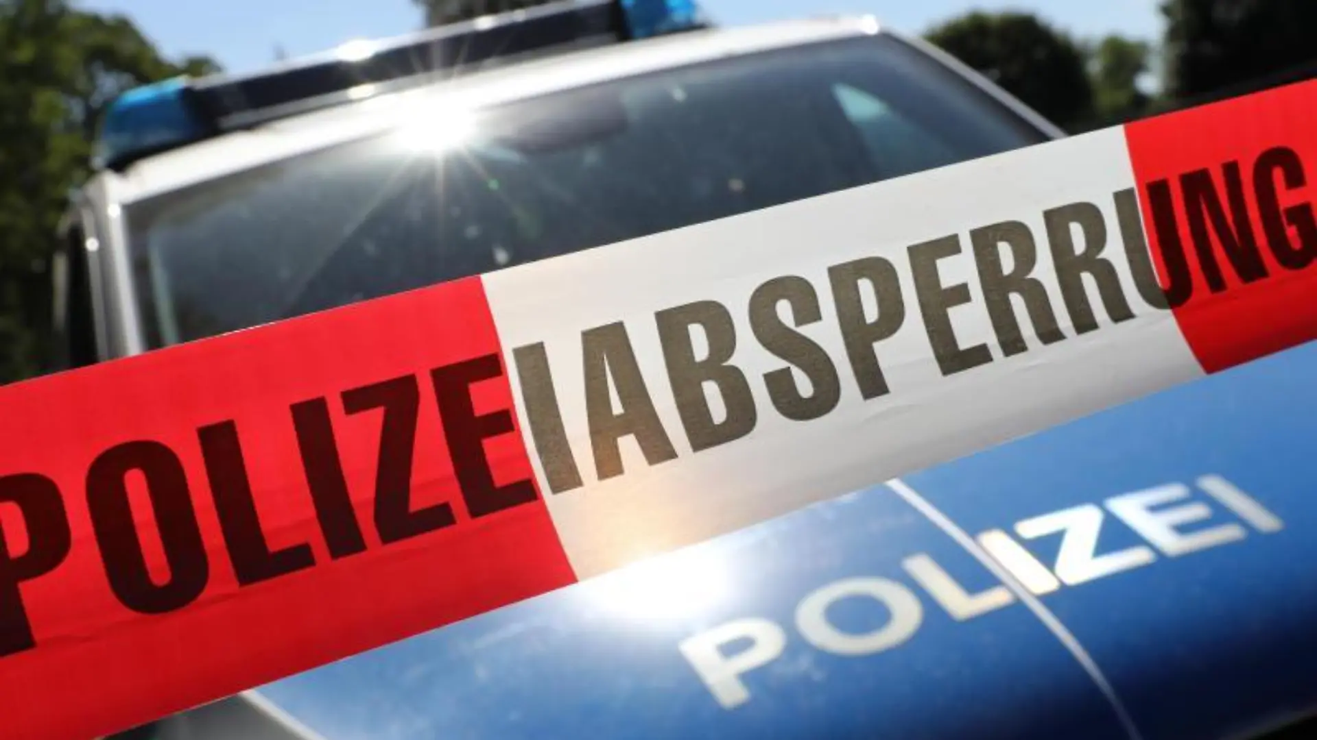 Eine Polizeiabsperrung hängt vor einem Polizeiauto