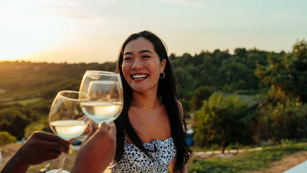 Happy asian woman having fun while toasting with wine at vineyard party