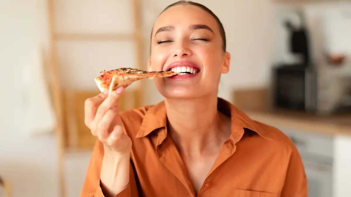 Eine Frau isst ein Stück Pizza.