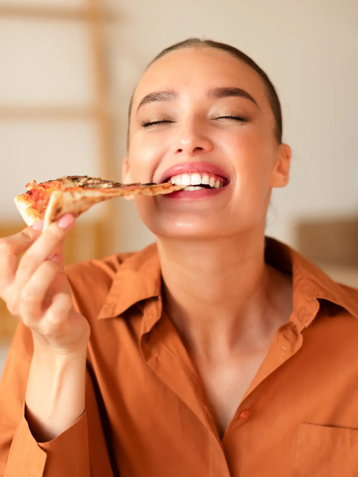 Eine Frau isst ein Stück Pizza.