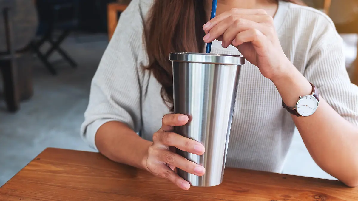 Closeup image of a woman drinking coffee in stainless steel cup