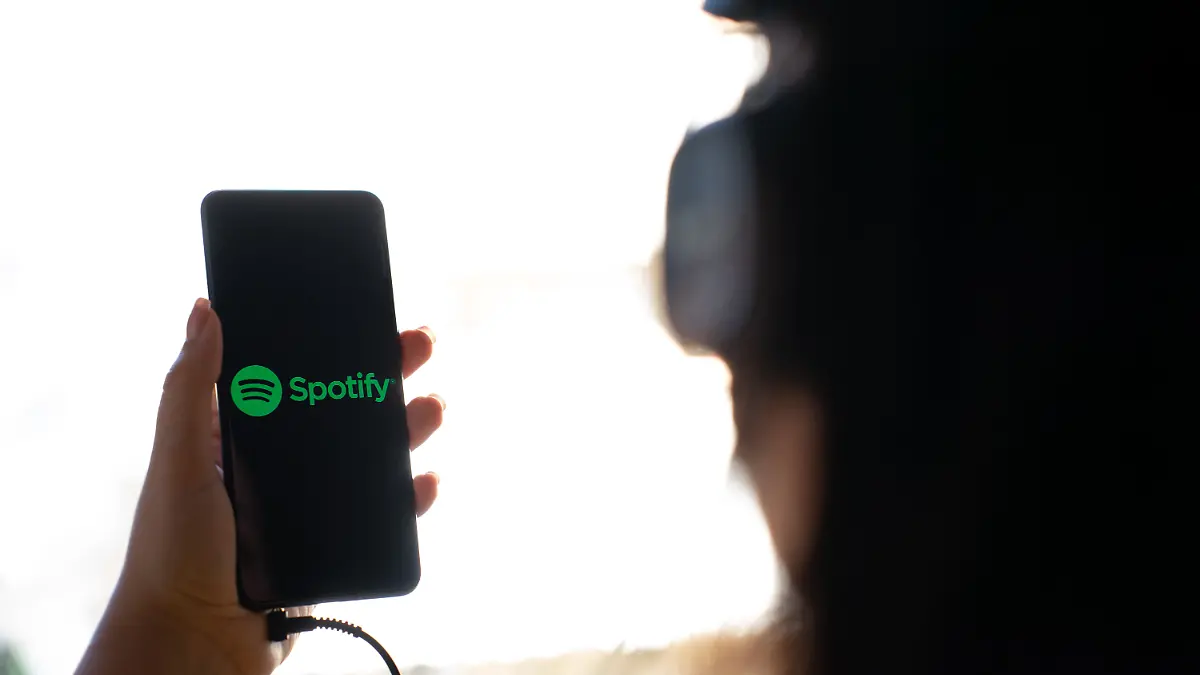 A woman holding a mobile phone with the logo of Spotify on its screen. (Photo by Nikos Pekiaridis/NurPhoto)
