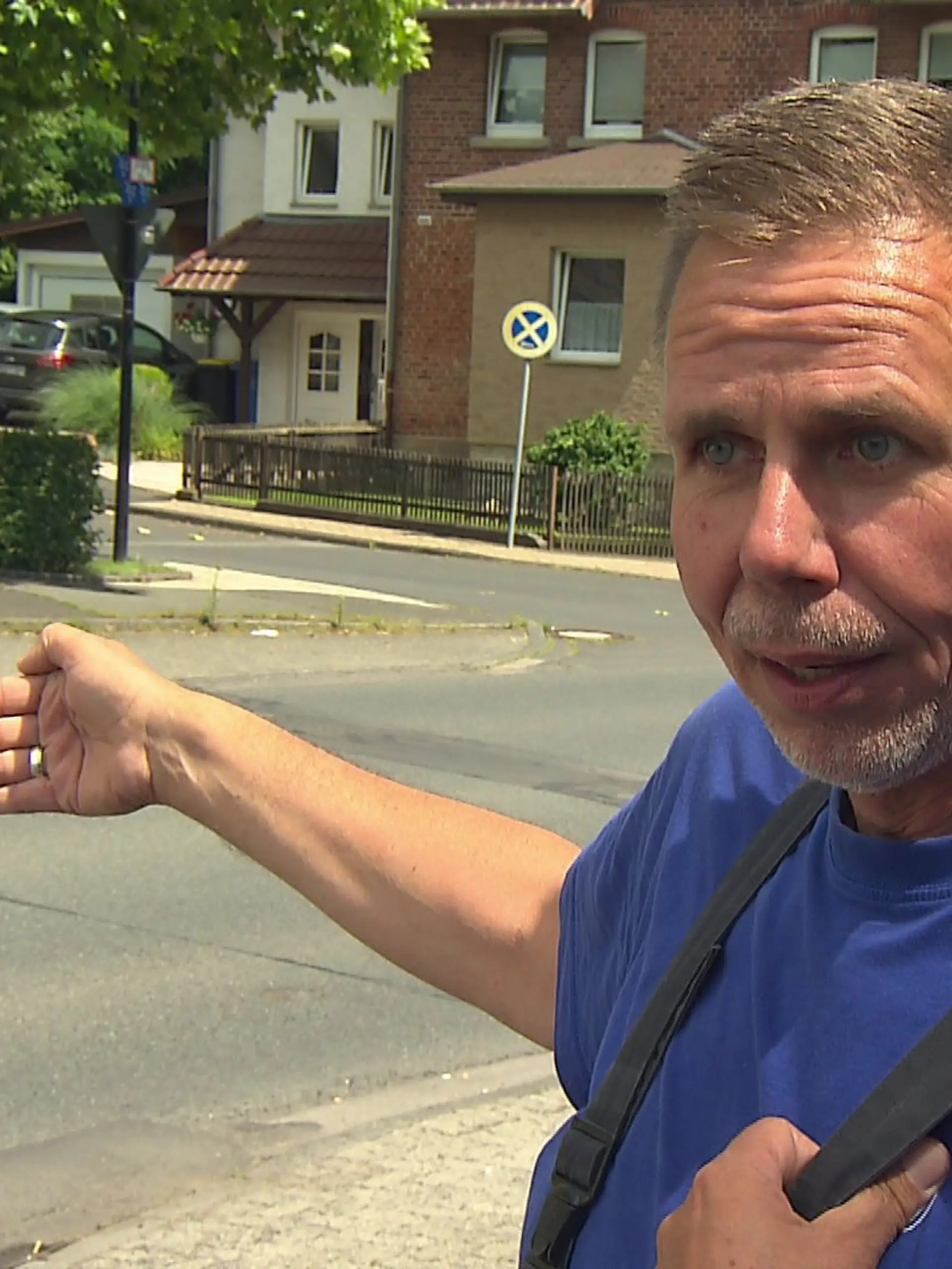 Ein Anwohner deutet mit seiner Hand auf die Straße.