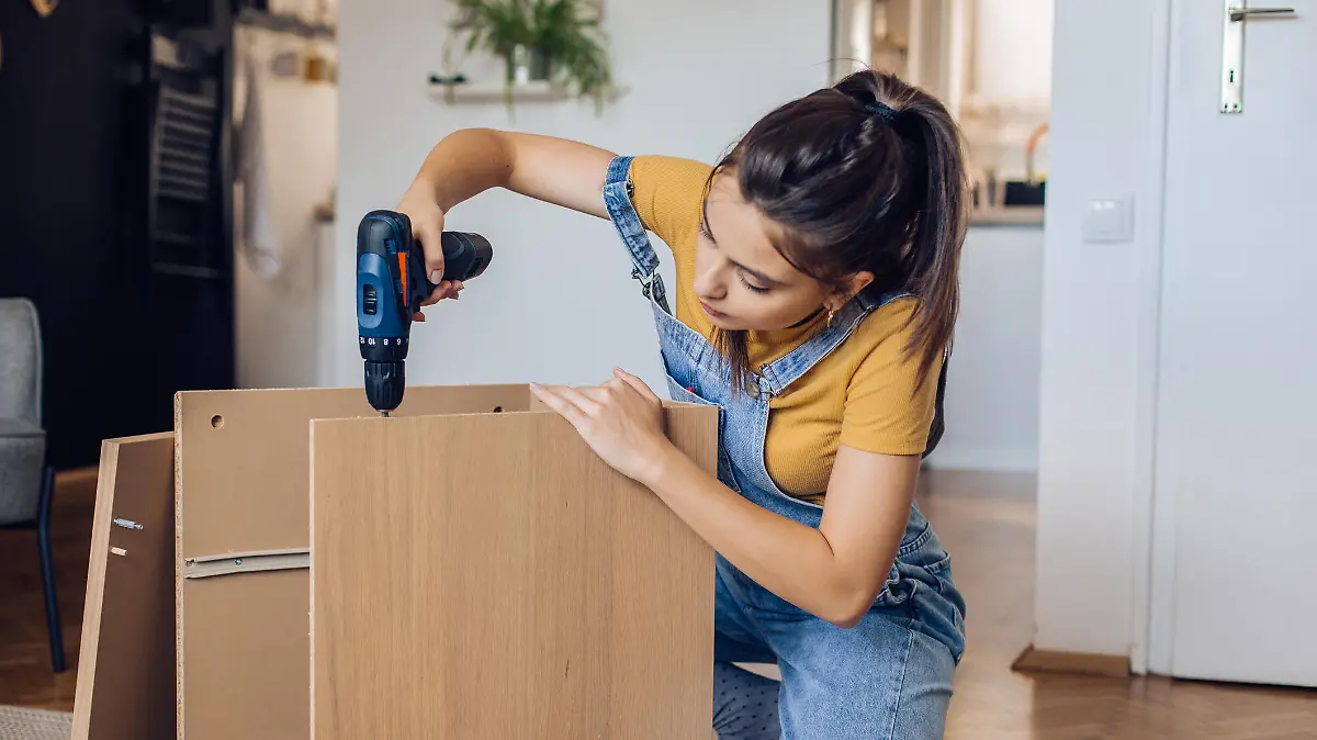 Teenage girl folding wooden furniture at home.
