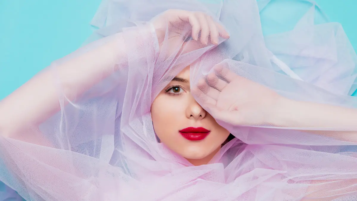 Young woman with pink tulle on blue background. Portrait
