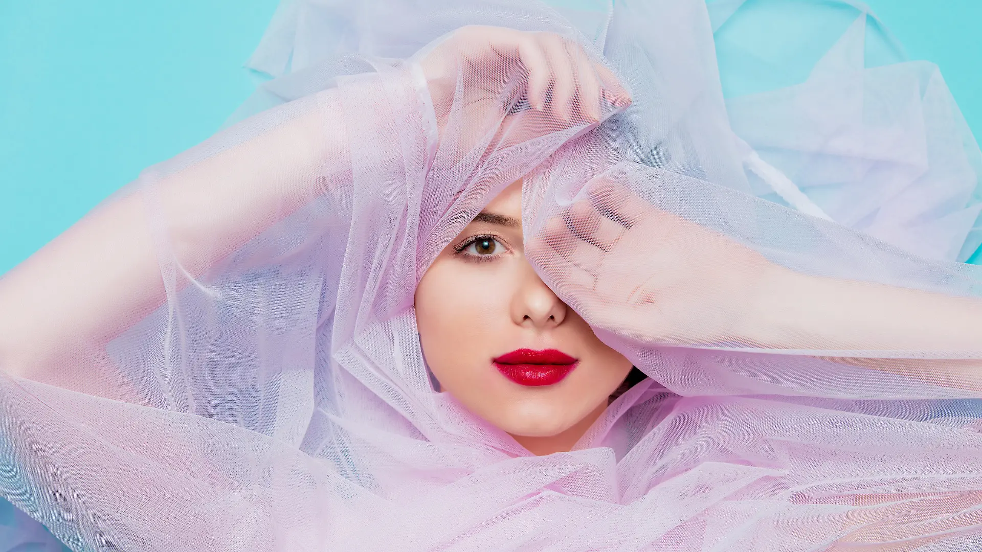 Young woman with pink tulle on blue background. Portrait