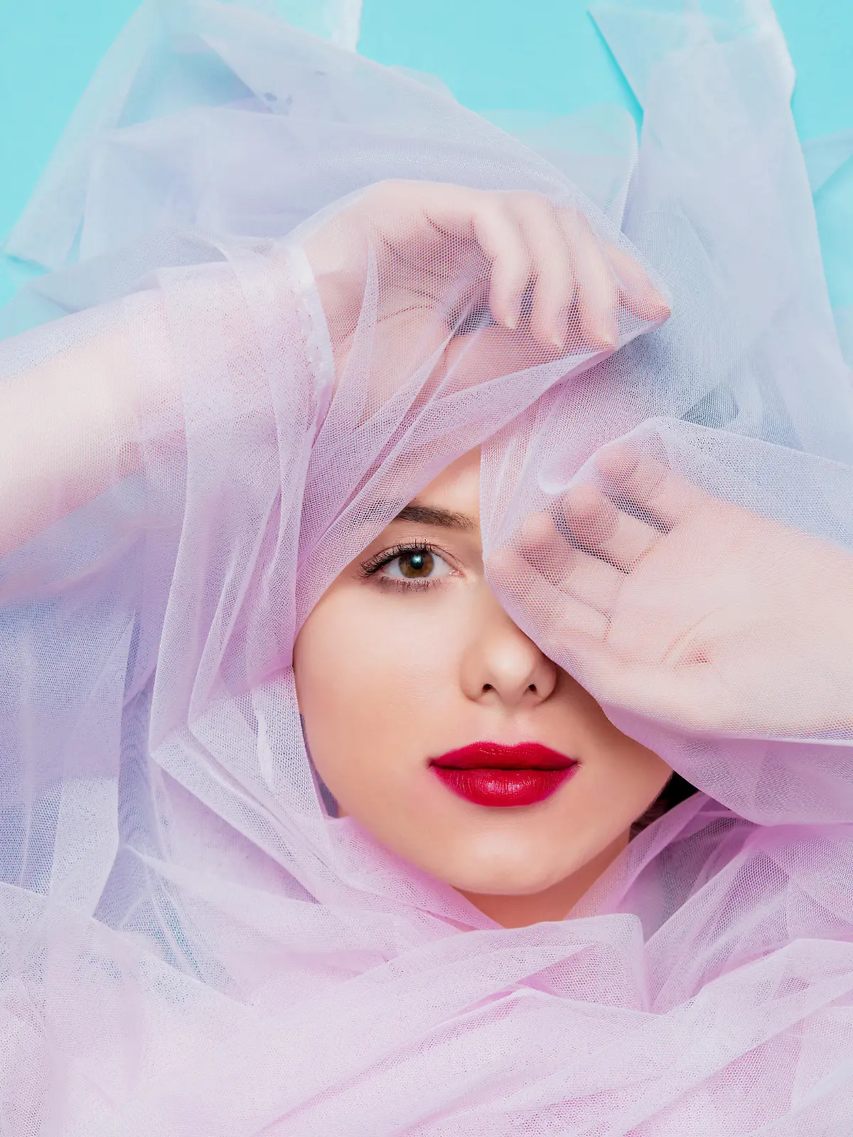 Young woman with pink tulle on blue background. Portrait