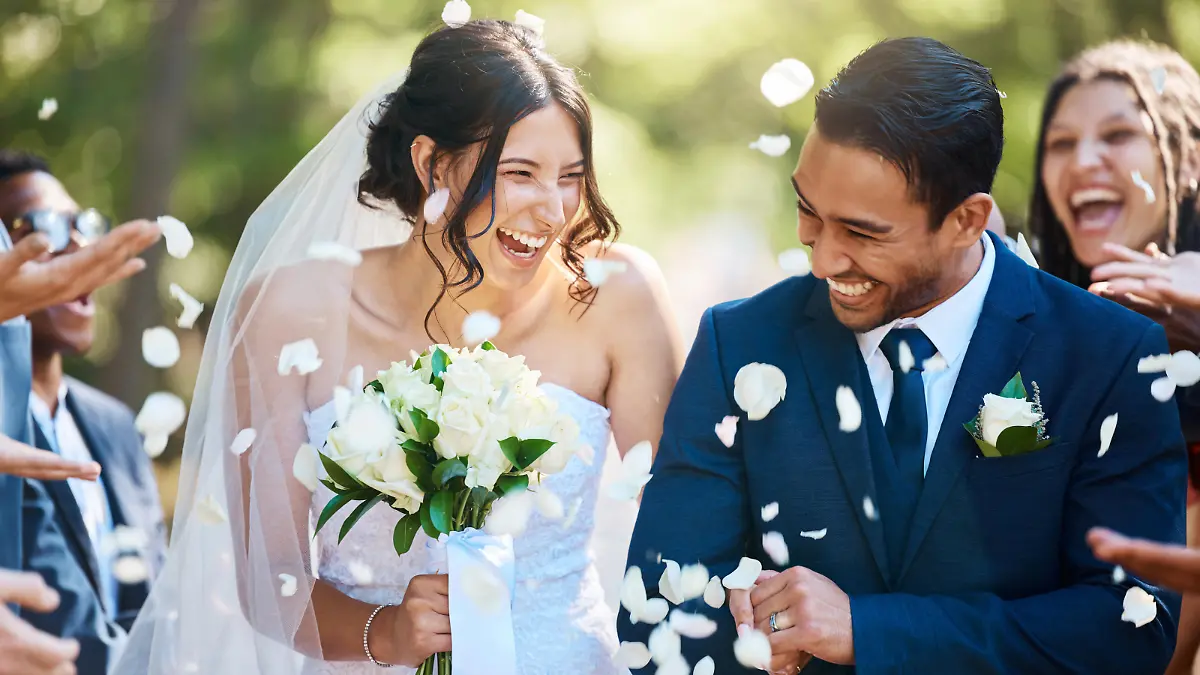 Guests throwing confetti over bride and groom as they walk past after their wedding ceremony. Joyful young couple celebrating their wedding day