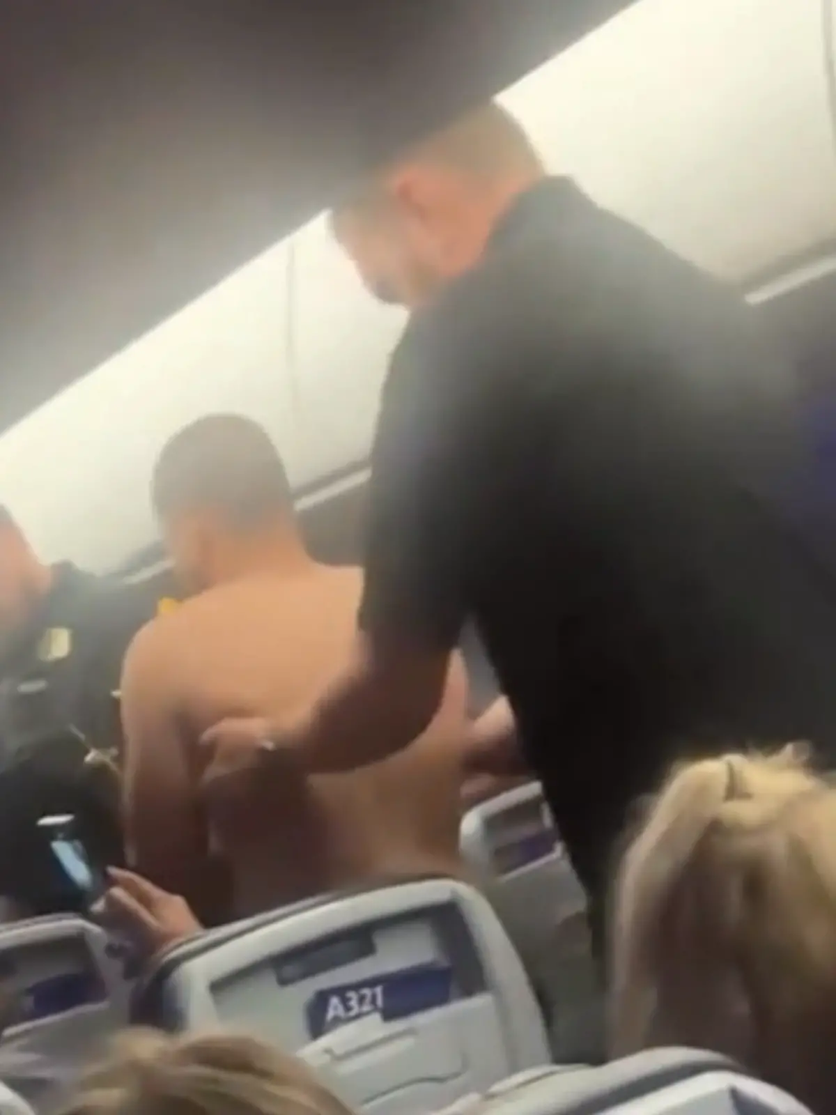 Ein Mann wird aus einer Flugzeugkabine abgeführt. 