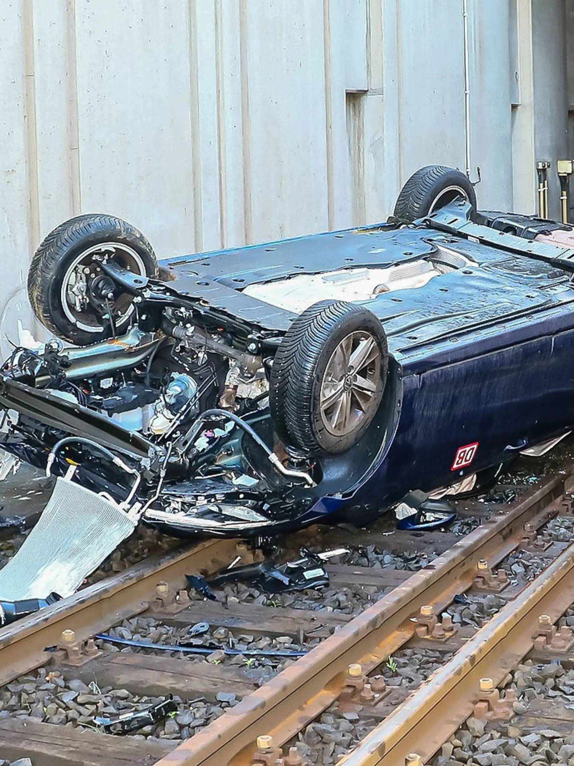 Ein Autowrack liegt auf Gleisen. 
