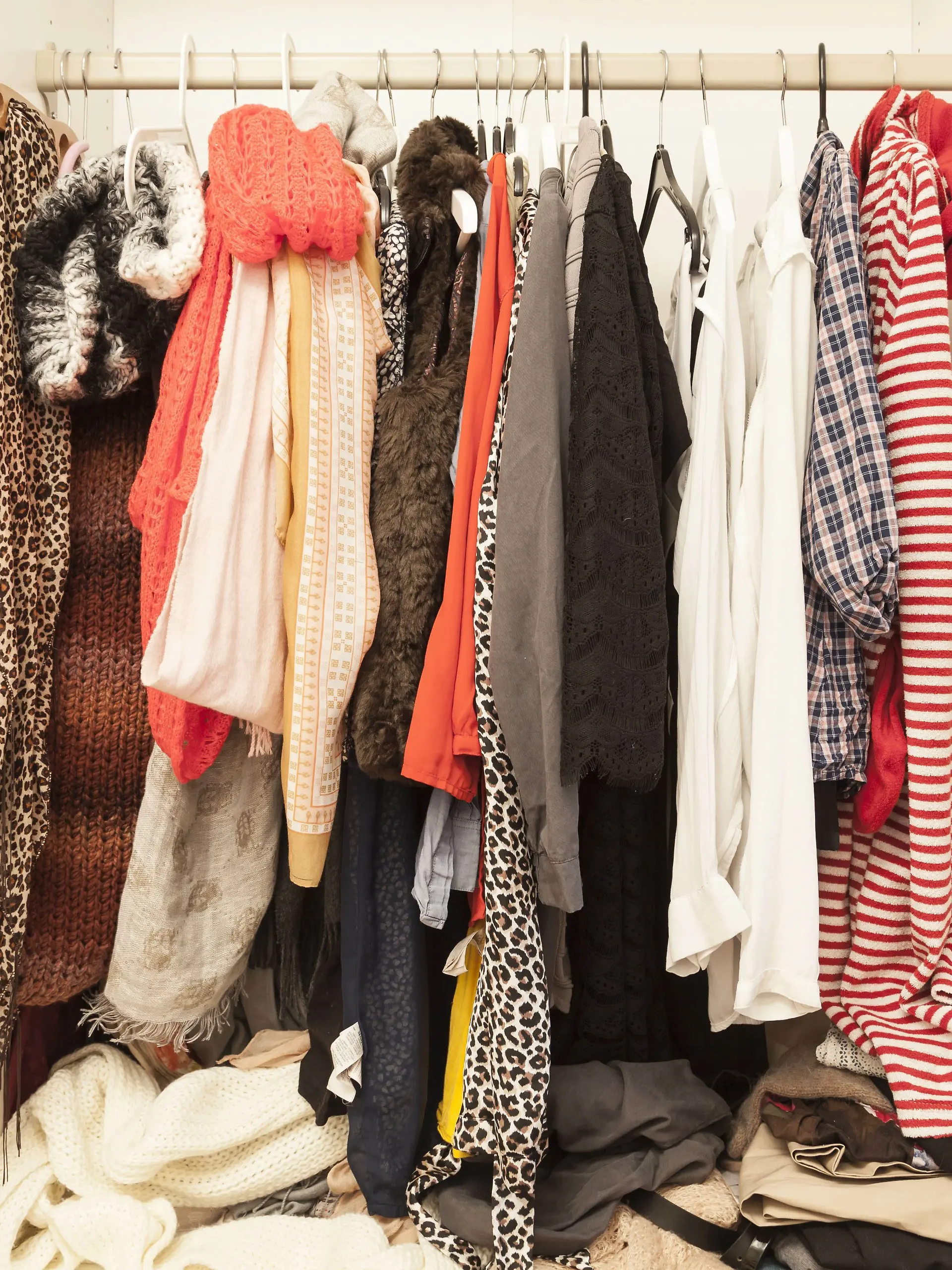 Ein offener Kleiderschrank mit vielen Kleidungsstücken. 
