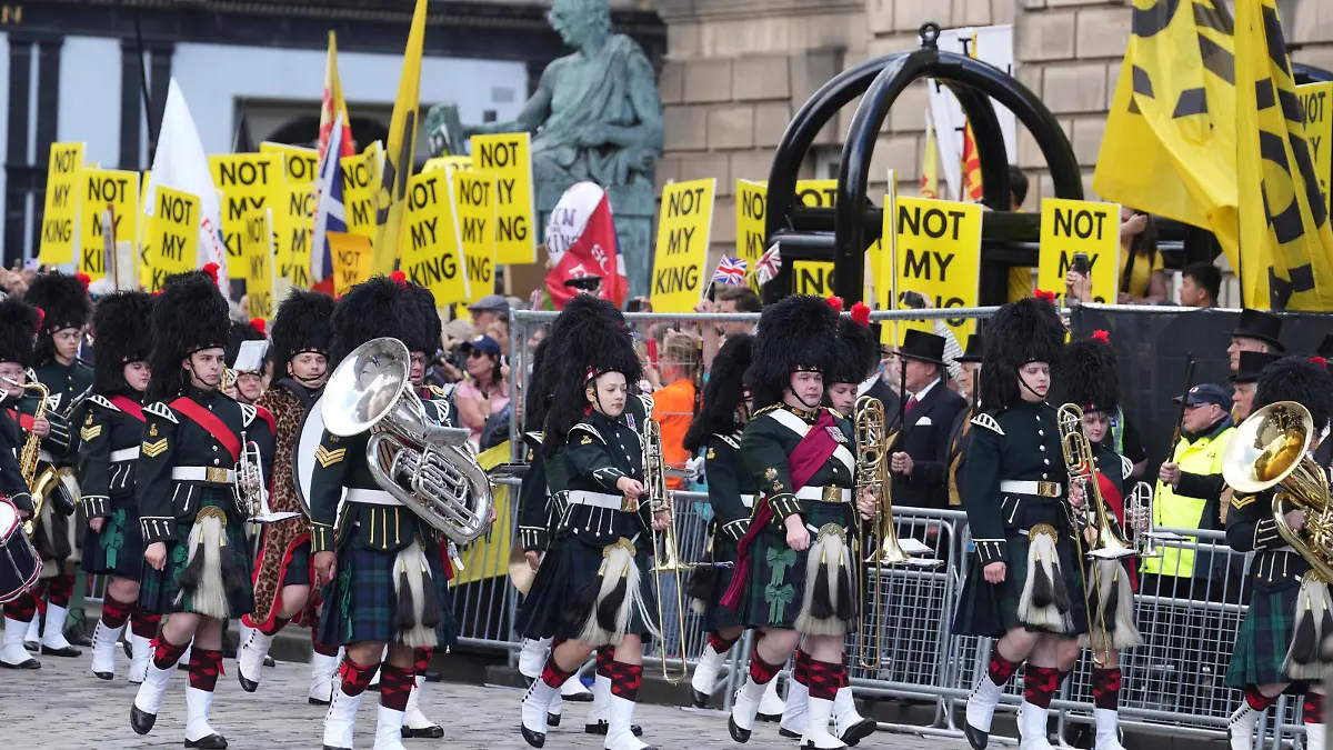 The Combined Cadet Force Pipes and Drums and the Cadet Military Band march past an anti-monarchy demonstration on The Royal Mile ahead of the National Service of Thanksgiving and Dedication for King Charles III and Queen Camilla, and the presentation of the Honours of Scotland, in Edinburgh, Wednesday, July 5, 2023. Two months after the lavish coronation of King Charles III at Westminster Abbey in London, Scotland is set to host its own event to mark the new monarch’s accession to the throne. (Danny Lawson/Pool Photo via AP)
