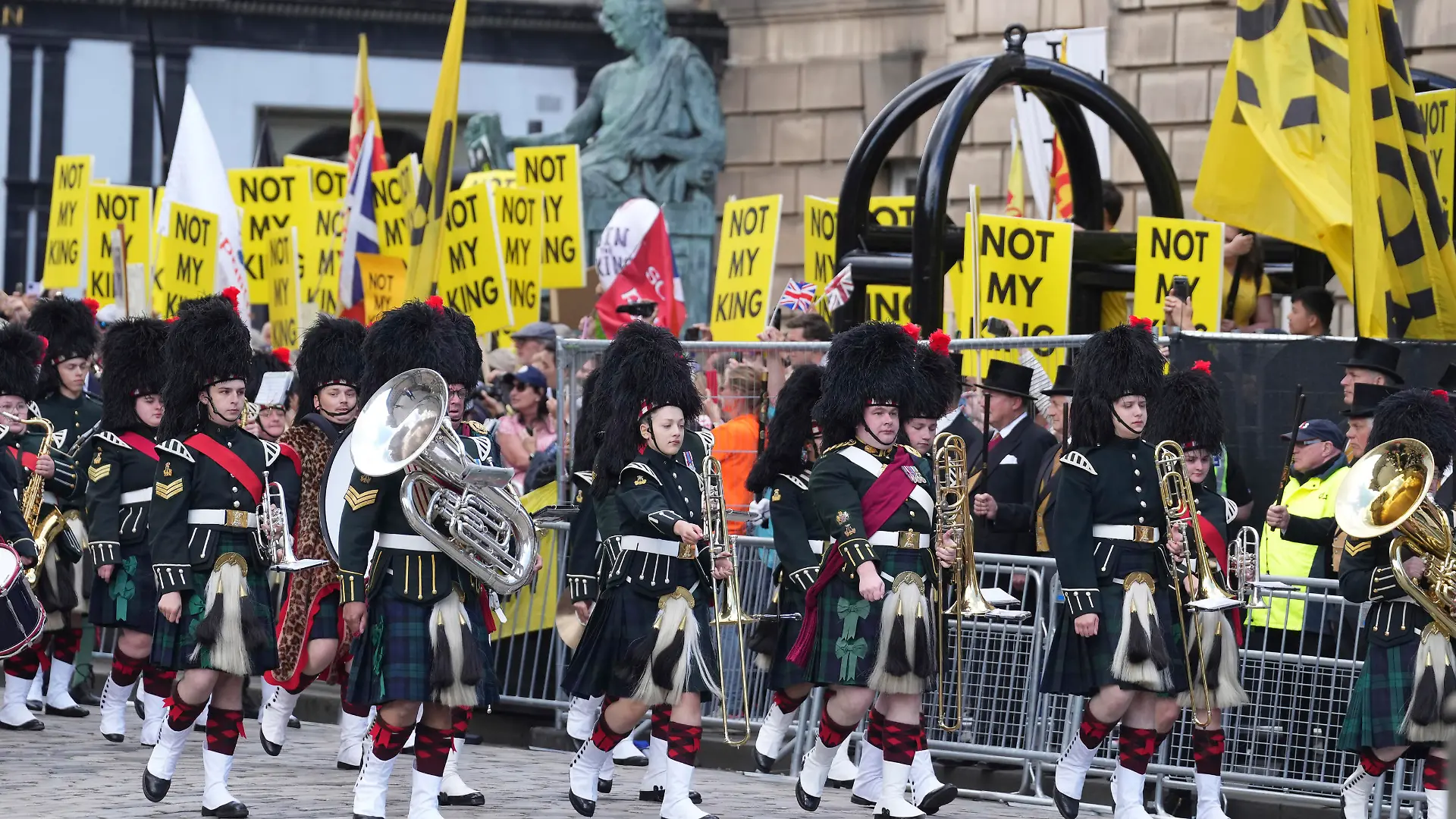 The Combined Cadet Force Pipes and Drums and the Cadet Military Band march past an anti-monarchy demonstration on The Royal Mile ahead of the National Service of Thanksgiving and Dedication for King Charles III and Queen Camilla, and the presentation of the Honours of Scotland, in Edinburgh, Wednesday, July 5, 2023. Two months after the lavish coronation of King Charles III at Westminster Abbey in London, Scotland is set to host its own event to mark the new monarch’s accession to the throne. (Danny Lawson/Pool Photo via AP)