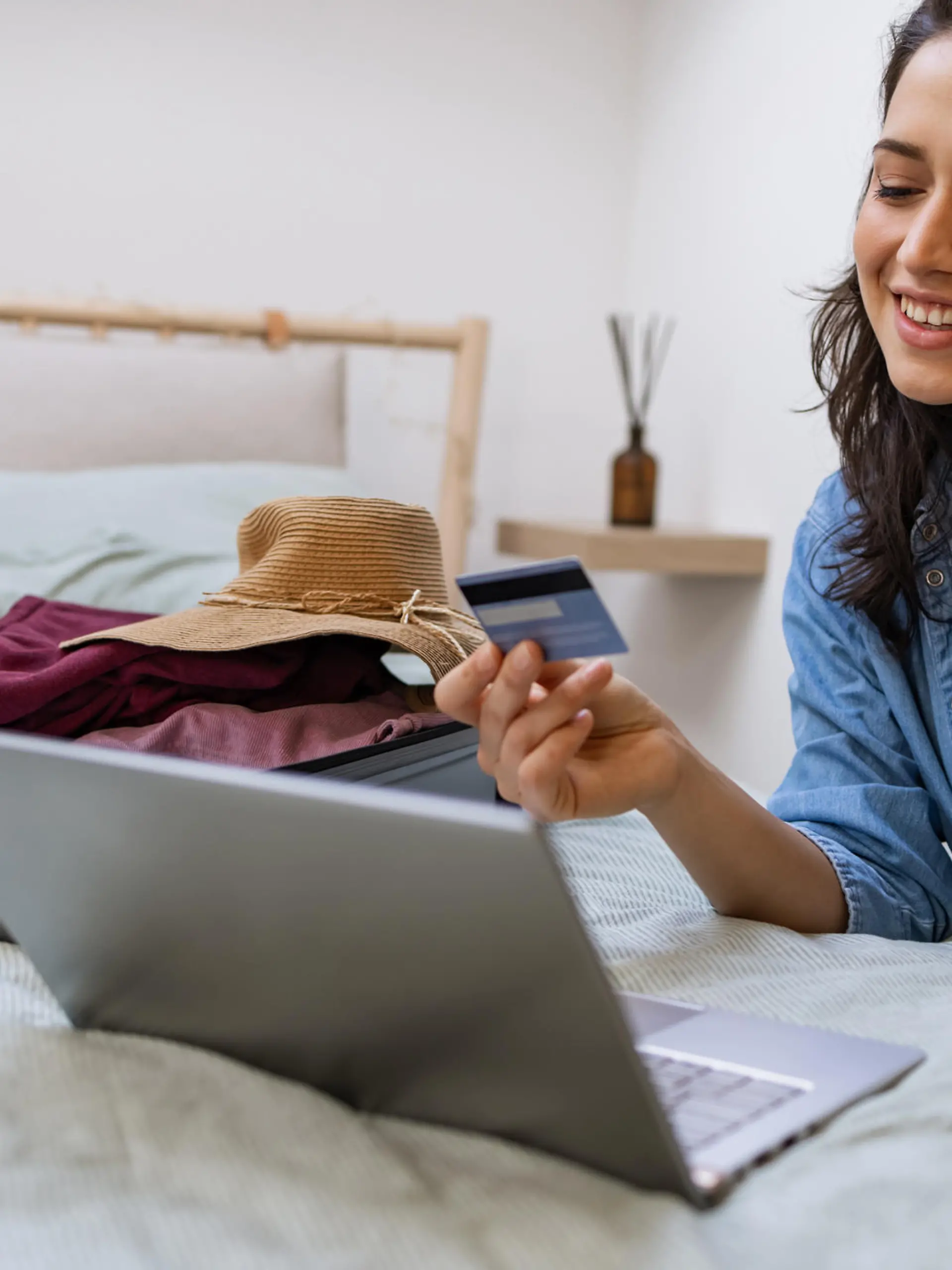 Happy woman talking won the phone phone and using laptop to make flight reservation