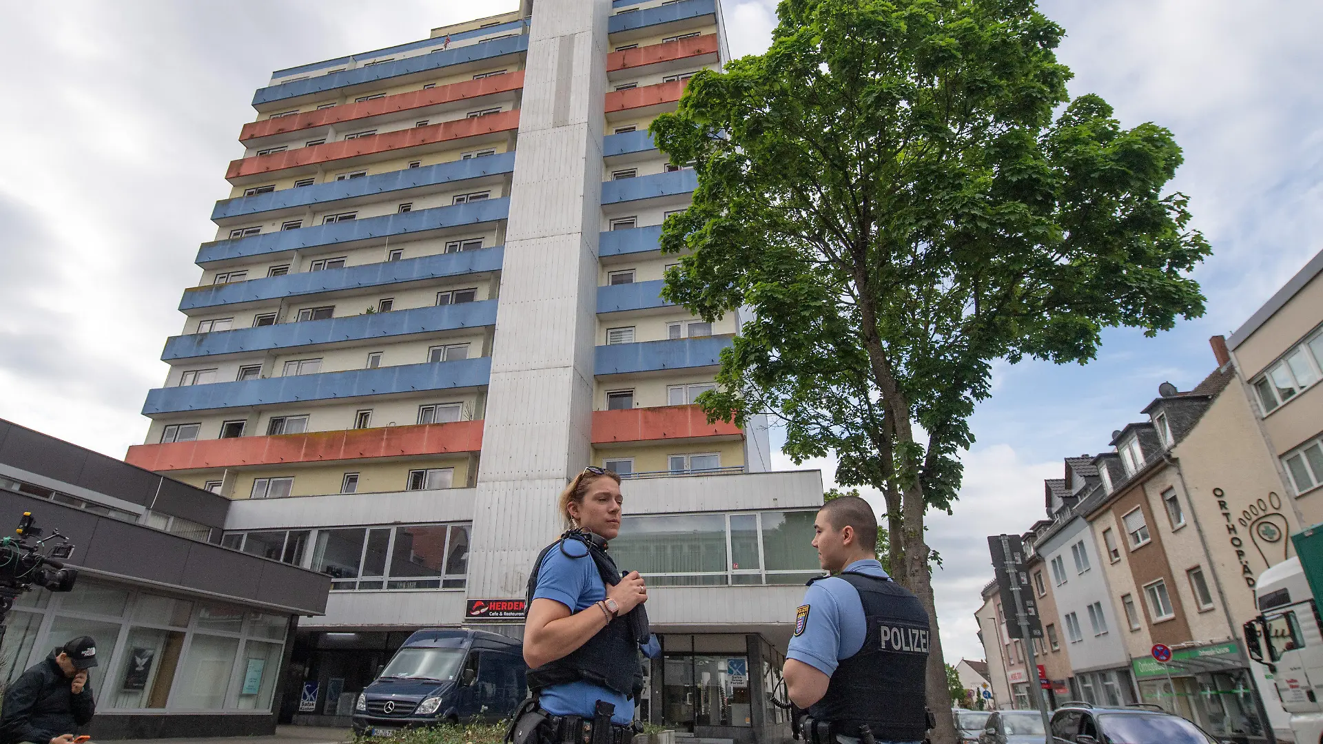 ARCHIV - 12.05.2022, Hessen, Hanau: Polizisten stehen vor einem Hochhaus, in dem 11.05.2022 zwei Kinder zu Tode gekommen waren. Die Polizei hat den Tatverdächtigen am 14.05.2022 in Frankreich festgenmmen. Es handele sich um den Vater der Kinder, sagte eine Sprecherin der Staatsanwaltschaft Hanau. Gegen ihn werde wegen Mordes ermittelt. Foto: Boris Roessler/dpa +++ dpa-Bildfunk +++