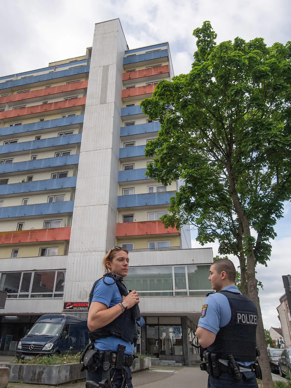 ARCHIV - 12.05.2022, Hessen, Hanau: Polizisten stehen vor einem Hochhaus, in dem 11.05.2022 zwei Kinder zu Tode gekommen waren. Die Polizei hat den Tatverdächtigen am 14.05.2022 in Frankreich festgenmmen. Es handele sich um den Vater der Kinder, sagte eine Sprecherin der Staatsanwaltschaft Hanau. Gegen ihn werde wegen Mordes ermittelt. Foto: Boris Roessler/dpa +++ dpa-Bildfunk +++